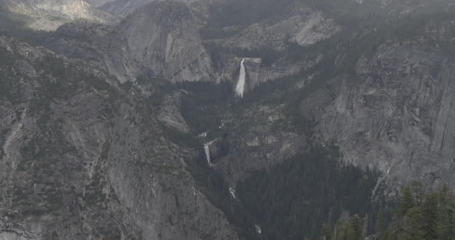 Snow falls over a mountain valley and the forest below