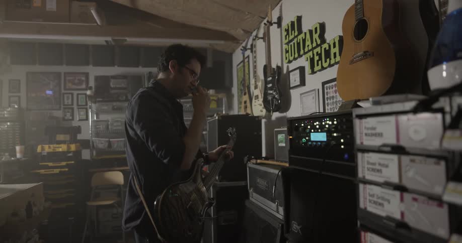 A man is plugging a cord into a guitar