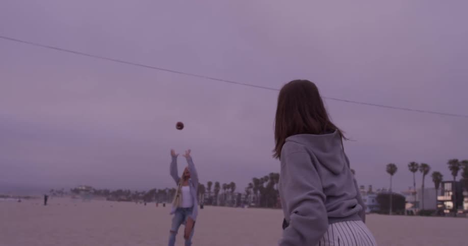 A woman throws a football to another woman who catches it