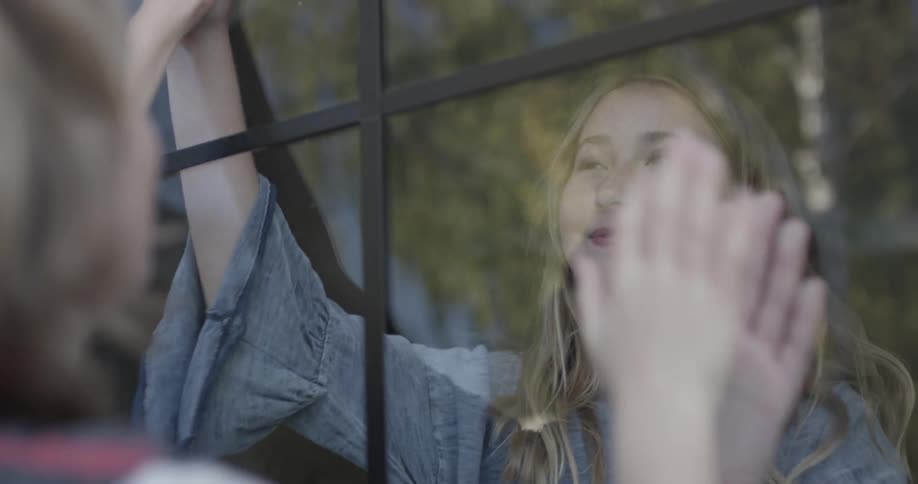 Boy and girl play with window pane in between them