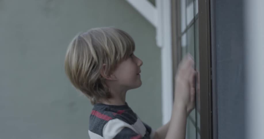 Two children are playing together on opposite sides of a window