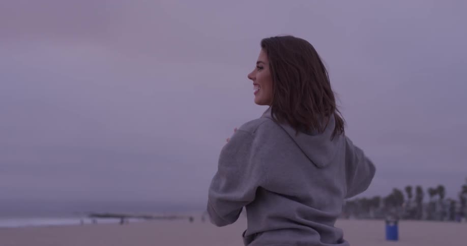 Woman catches a football and throws it on the beach