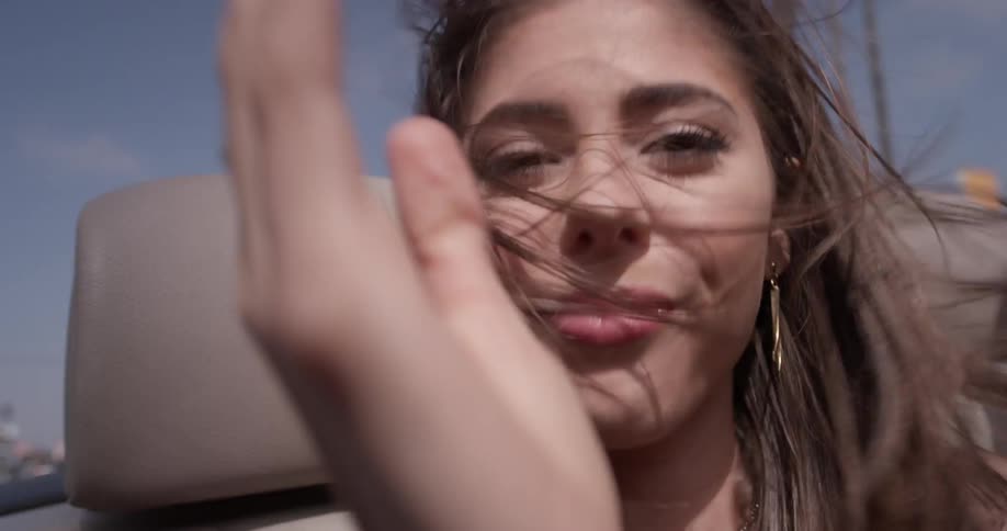 Woman sips out of a cup while riding in a convertible