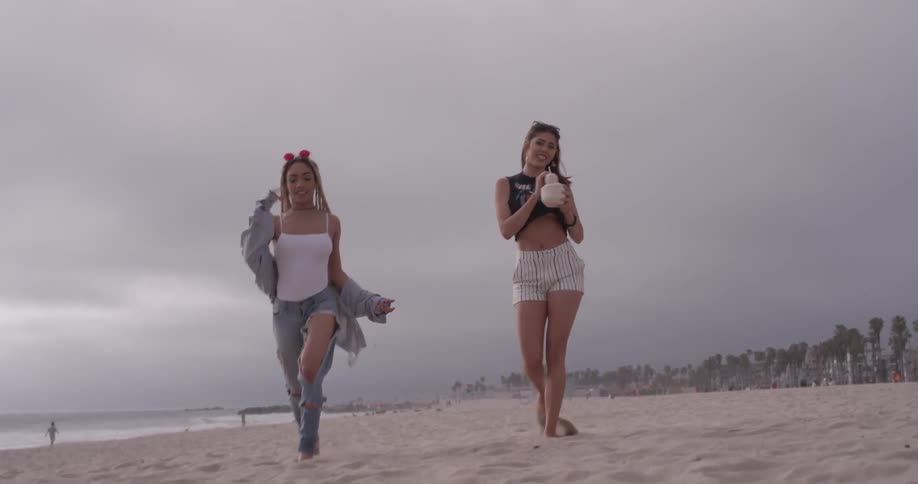 Two women are skipping on the beach