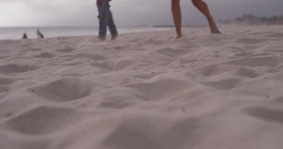 Two people are walking in the sand near a beach