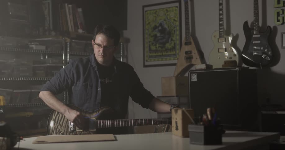 Man working on a guitar then playing it