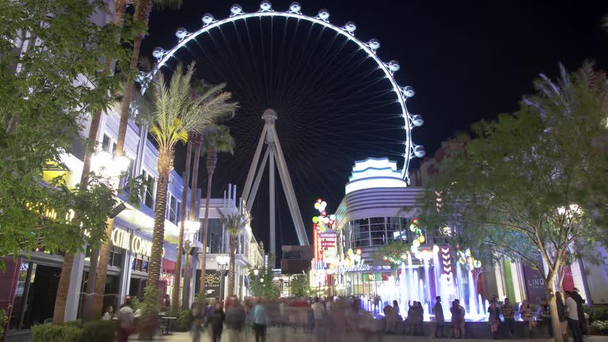 People walking in city square, with ferris wheel in the background