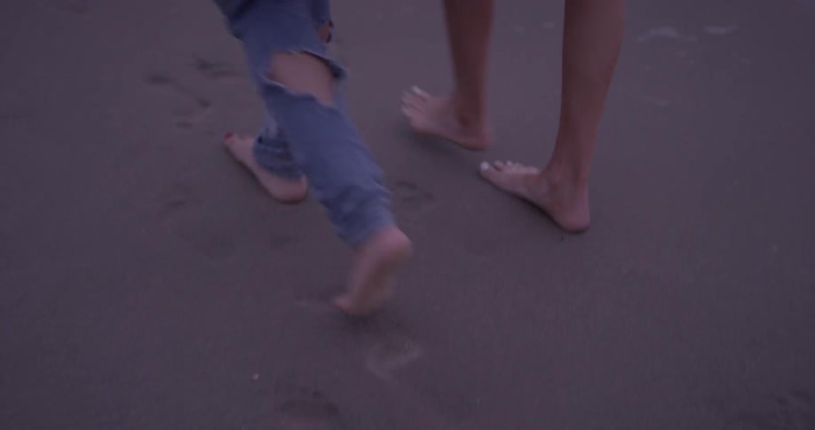 Two women walking around on the beach at dusk