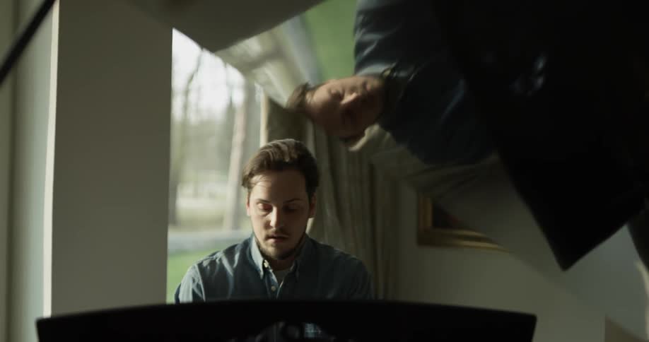 Man plays piano in front of a window during the day
