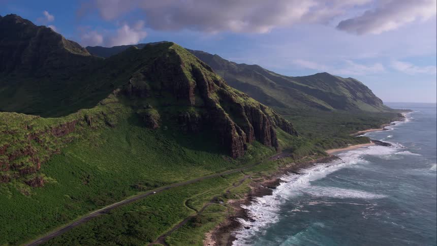 Aerial shot of green mountains next to the ocean