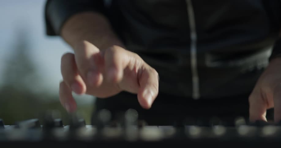 Man wearing a wrist watch plays piano outside on a sunny day