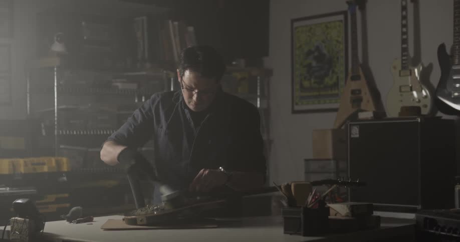Man Making Guitar In Workshop