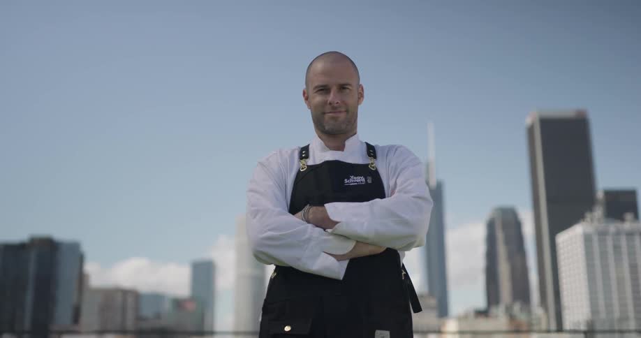 Chef wearing an apron stands on top of a building overlooking the city