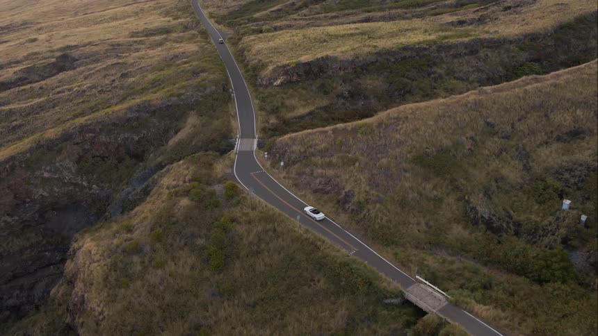 Aerial shot of a car driving along a road in the countryside