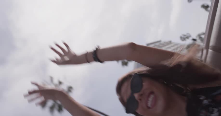 A woman dances happily in the back seat of a convertible