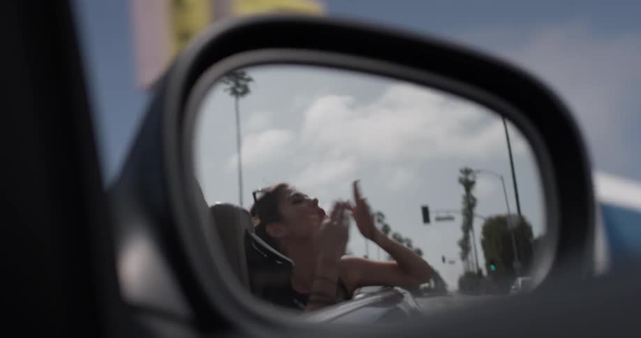 A woman waves and blows a kiss from a vehicle