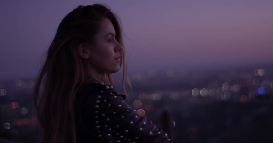 Woman standing at the top of a hill at dusk