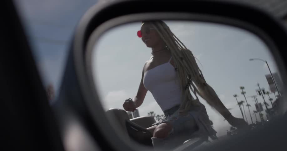 A woman is dancing on a car outside