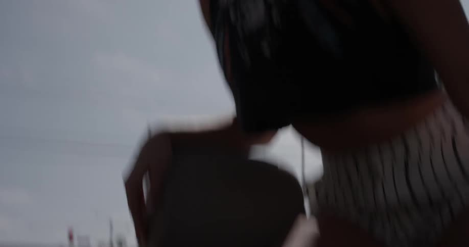 A woman sitting on the back of a convertible dancing while the car is driving