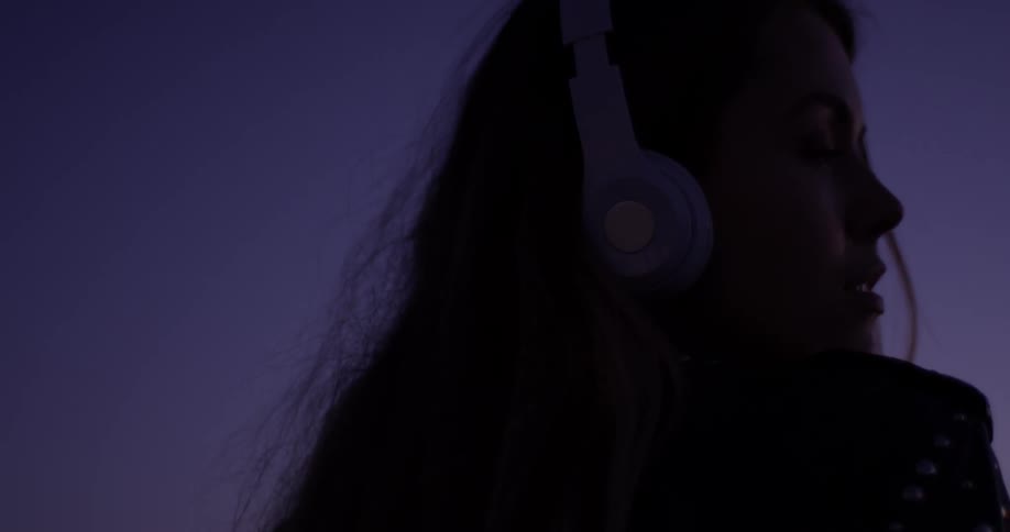 A woman is wearing headphones outside