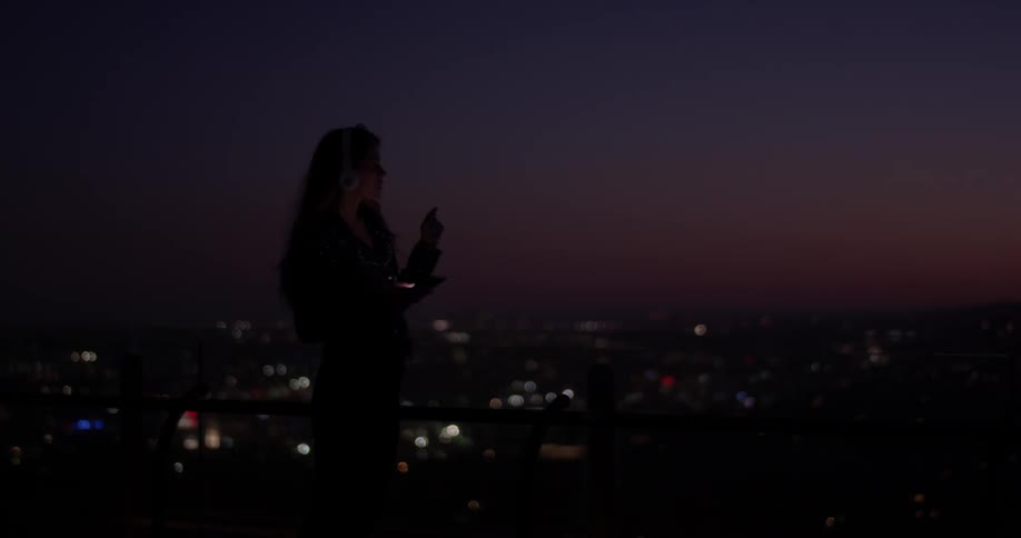 A woman is outside on her phone at night