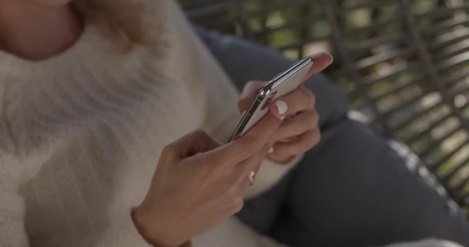 A woman typing on a phone sitting outside