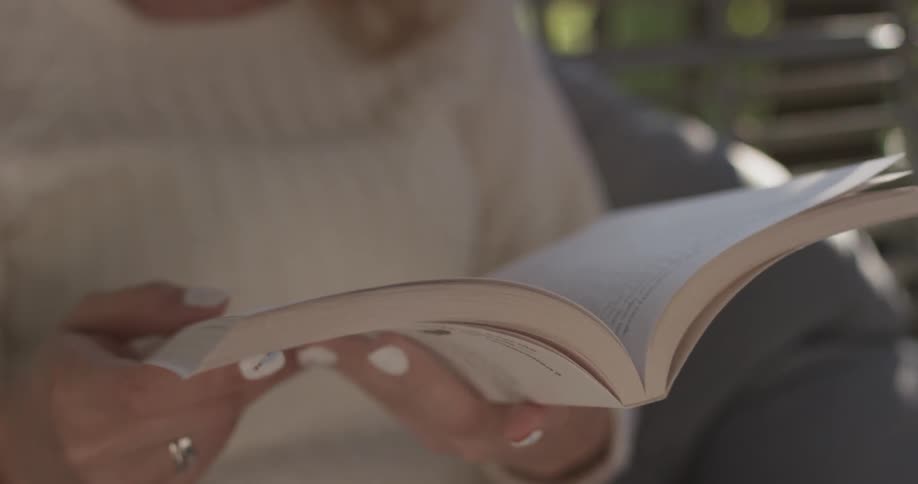 Woman sits outside on a sunny day reading