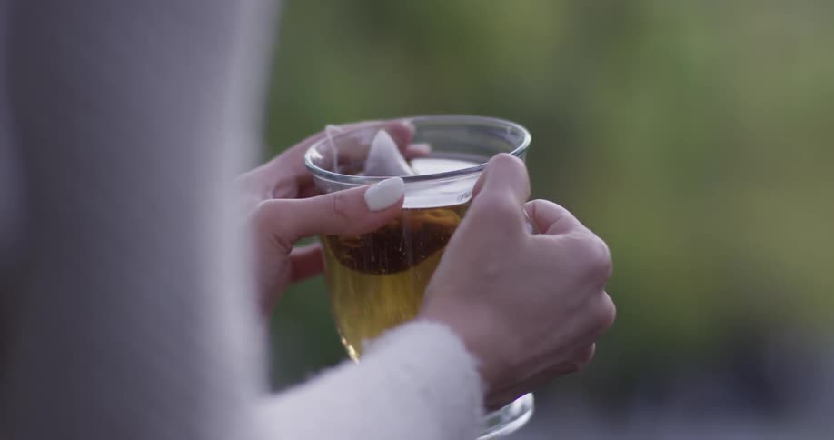 A woman is holding a cup outside