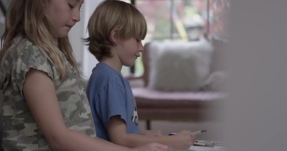 A boy and a girl sit at a low table and color