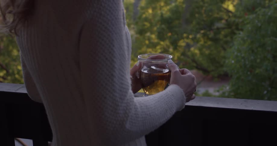 A woman standing on a porch drinking tea