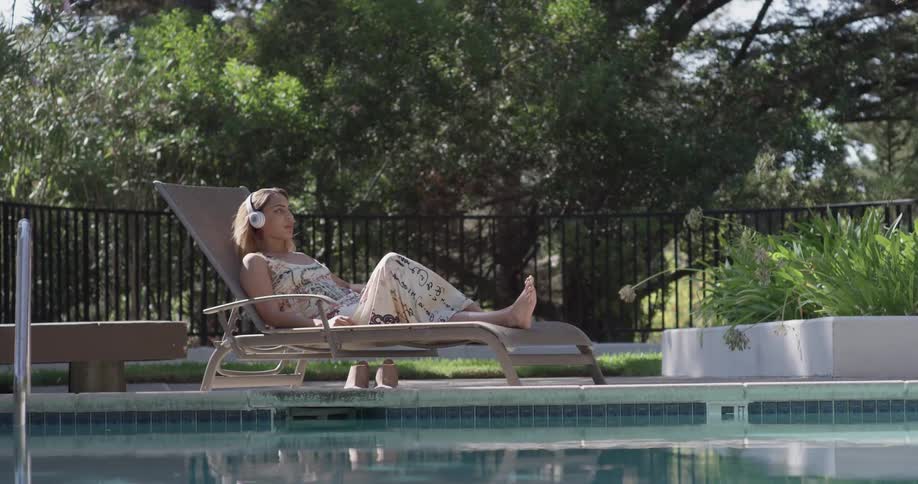 A woman is putting headphones on while sitting outside