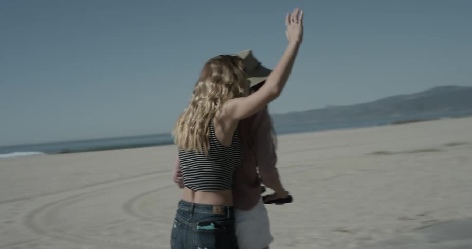 Two girls smile as they ride a scooter along the beach