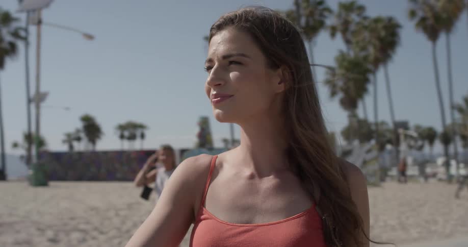 Woman standing at the beach looking in the distance while others walk around her