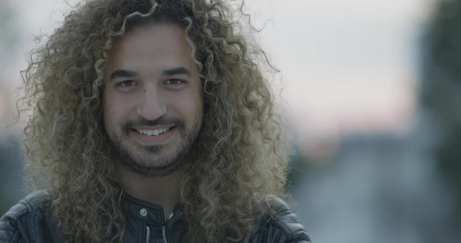 Man looks up and smiles into camera on a sunny day