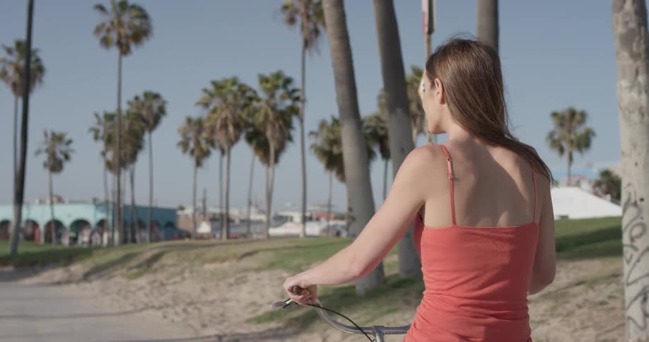 A woman smiling as she rides a bike down a pathway