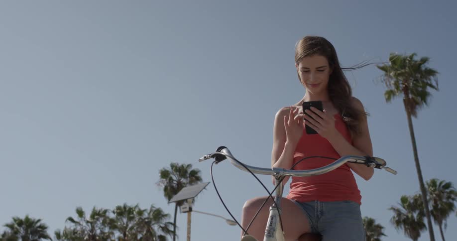 A woman sitting on her bike and reading on her smartphone