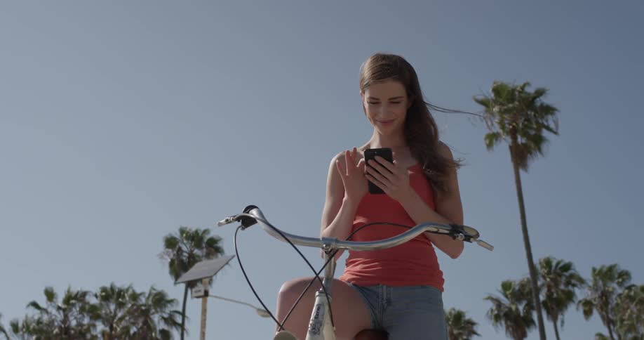 A woman is on her phone while sitting on a bicycle