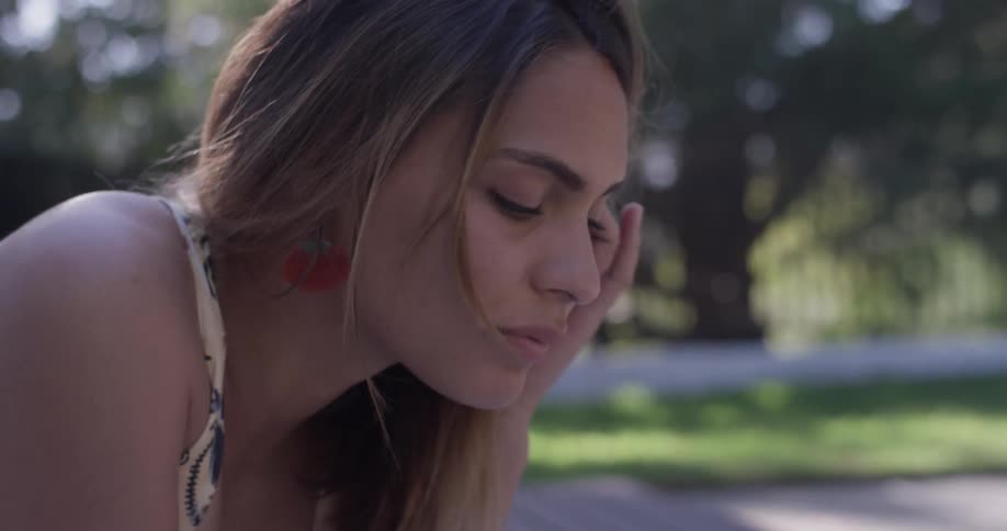 A woman looks down at something and rests her chin in her palm
