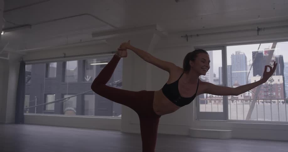 A woman does a yoga pose in an empty room
