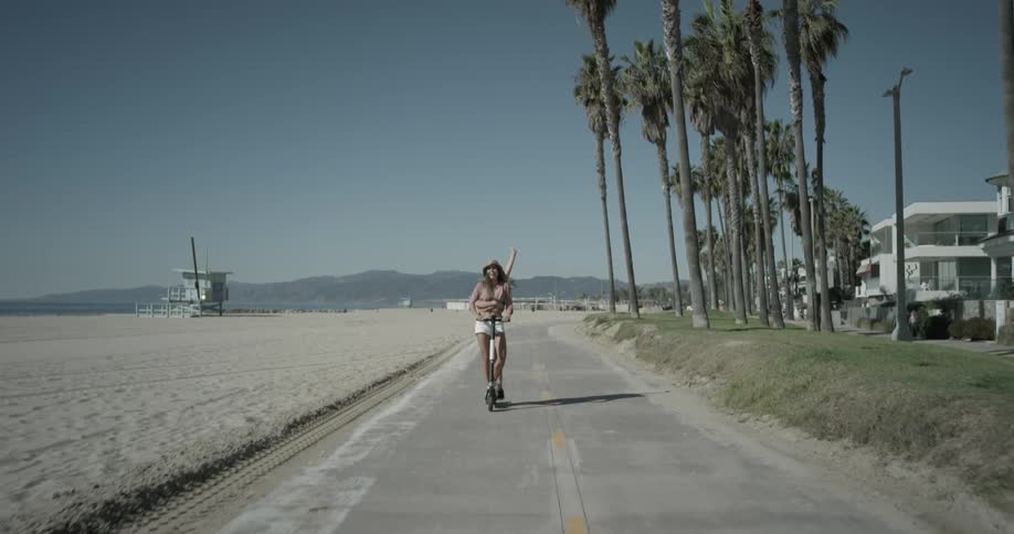 Two women riding on a scooter next to the beach