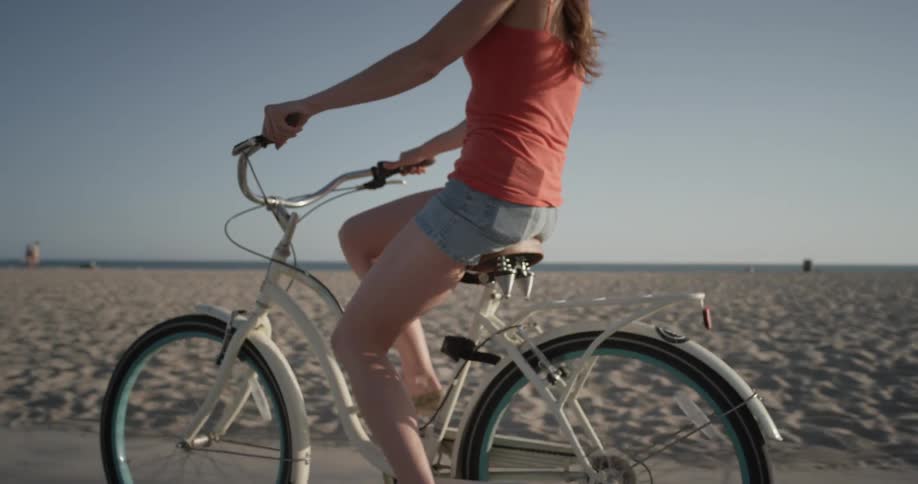 Woman riding a bicycle next to the beach