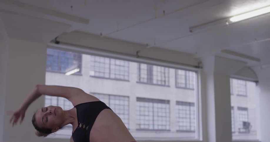 A woman in a black sports bra stretches