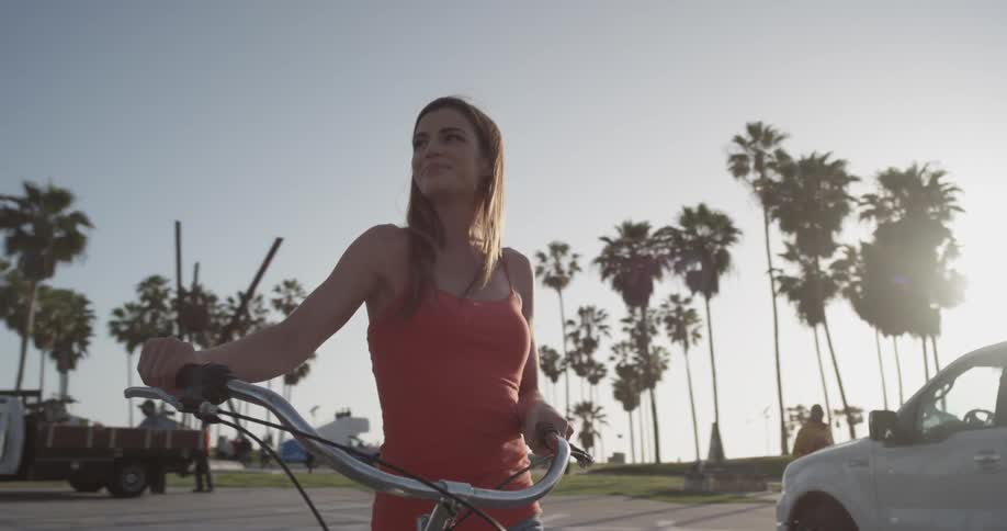 Woman pushes her bike through the city on a sunny day