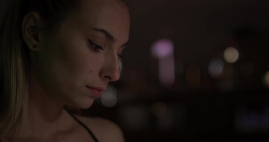 Woman looks at her phone outside at night