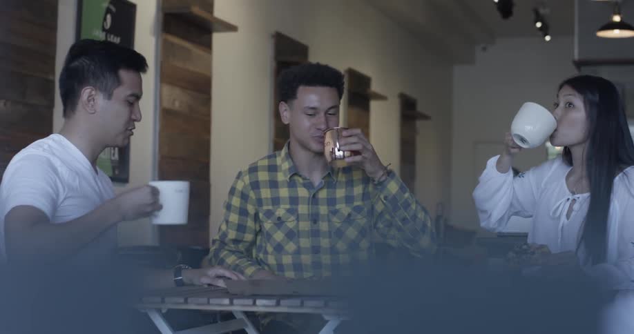 Two men and one woman make a toast with their mugs