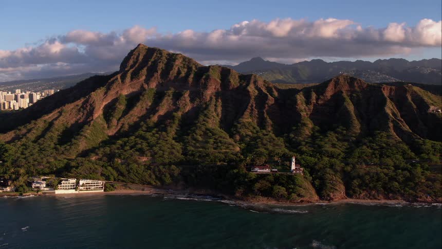 A villa is sandwiched between the ocean and tall green hills