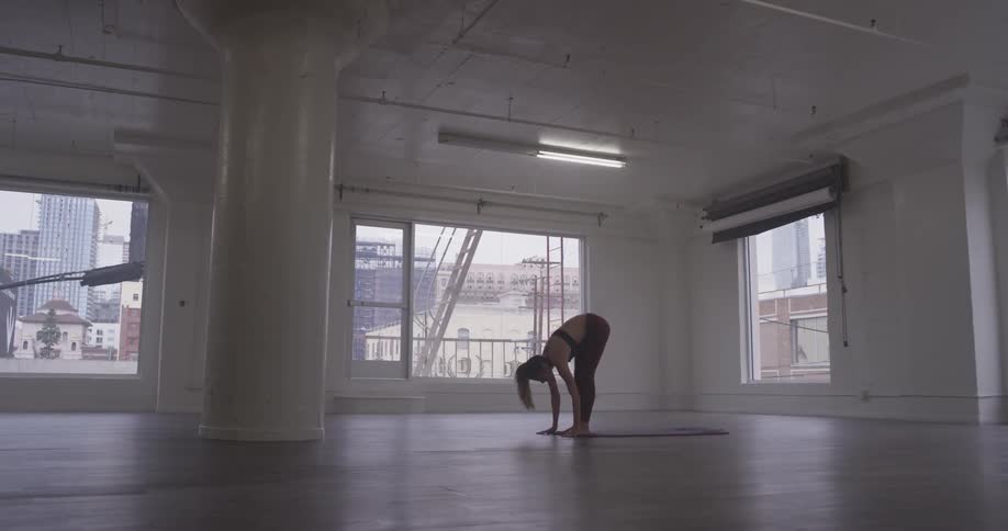 A woman is bent over touching the floor and her ankles