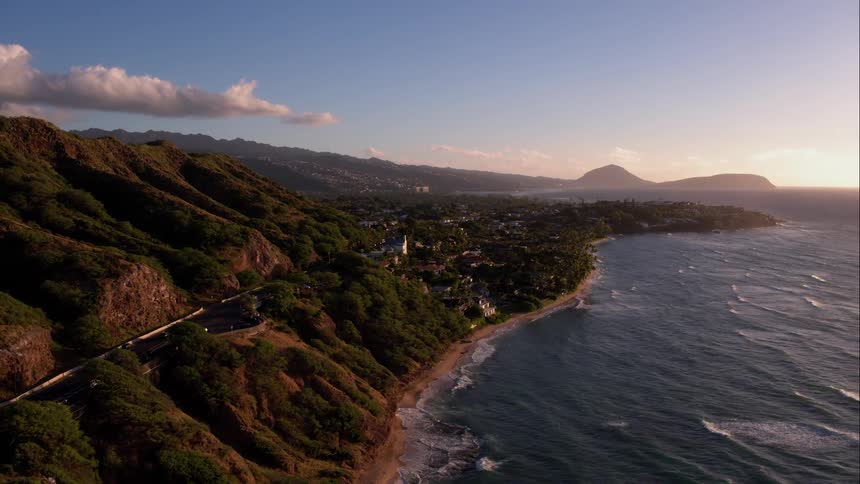 Cars drive on a hillside over calm waves below