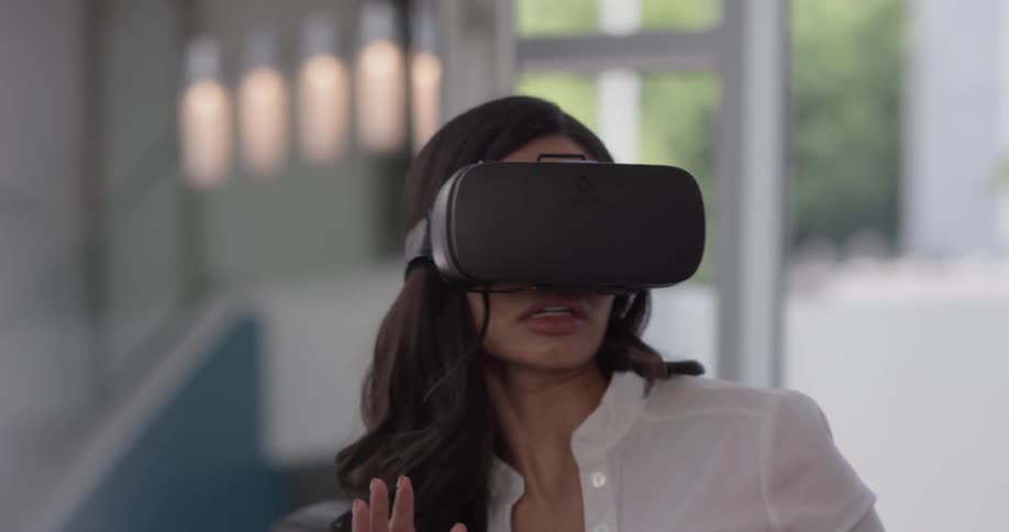 A woman puts on some virtual reality goggles and looks around shocked by what she sees