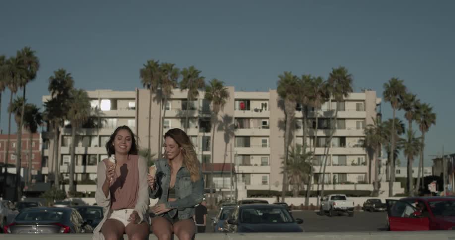 Two women are having ice cream outside of a building